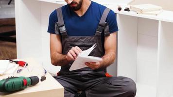 Revealing shot of confused handyman while reading instructions video