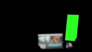 Smartphone de pantalla verde en una habitación oscura video
