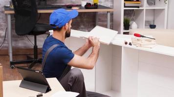 trabajador masculino siguiendo las instrucciones de los muebles de la tableta video