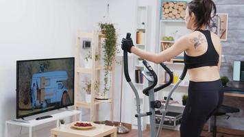 Young woman watching tv and doing a workout