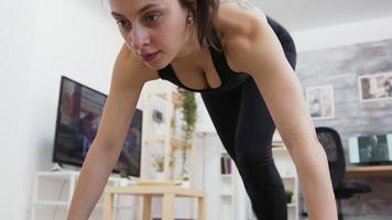 Young woman at home doing mountain climbers workout video