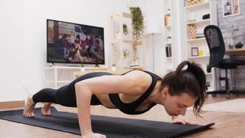 Young woman focused on her breathing while doing push-ups video