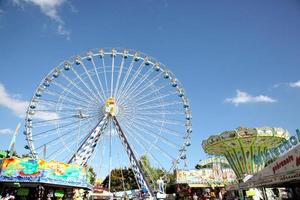 A beautiful ferris wheel on a holiday surrounded by rides photo