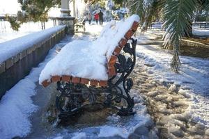 vacaciones de invierno en el parque, nieve en un banco de madera. foto