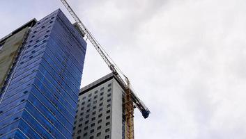 the construction site with a crane in front of the skyscraper buildings. a high building with wall glasses is under construction. photo