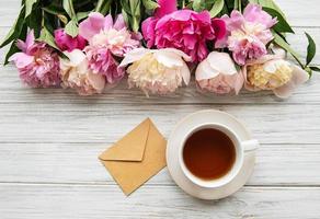 Cup of tea and pink peonies photo