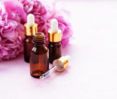 Aromatherapy essentials oils and pink peonies photo