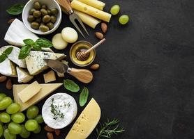 Various types of cheese, grapes, honey and snacks photo