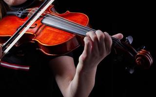 violín instrumento musical clásico. manos de jugador clásico sobre un fondo negro. detalles de tocar el violín foto