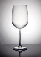 A glass of wine on a gray background, standing on a black stand with reflection photo