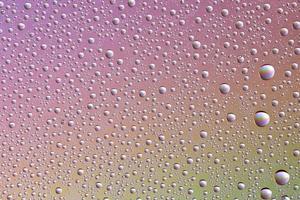 Drops on glass of different sizes and colors on a colored background, texture photo