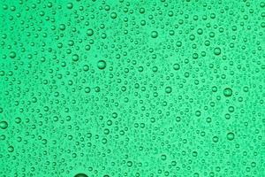 Drops on glass of different sizes and colors on a colored background, texture photo