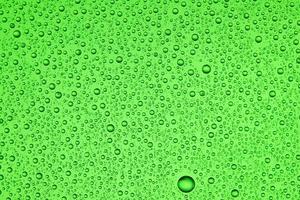 Drops on glass of different sizes and colors on a colored background, texture photo