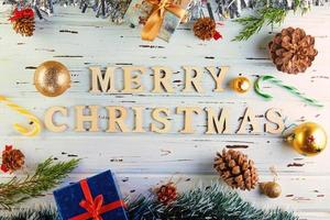 feliz navidad y próspero año nuevo concepto. plano de accesorios navideños. decoración del árbol de navidad y feliz navidad inscripción foto