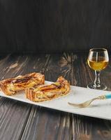 Tarta de manzana con rodajas de vainilla en rodajas con vaso de licor, sobre fondo de madera. comida gourmet francesa foto