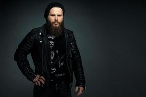 portrait of handsome bearded man in leather jacket and hat looking at the camera photo