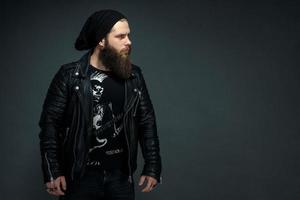 portrait of a handsome bearded man in a leather jacket and hat looking to the side photo