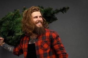 handsome man with long hair holding a synthetic christmas tree photo