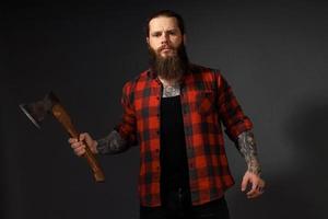 handsome man with long hair with an ax in his hands on a dark studio background photo