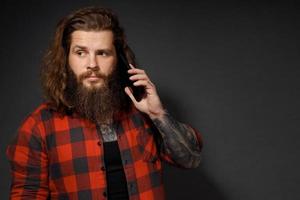 handsome man with long hair holding a mobile phone by his ear photo