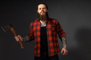 handsome man with long hair with an ax in his hands on a dark studio background photo