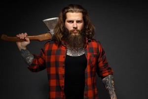 handsome man with long hair with an ax in his hands on a dark studio background photo