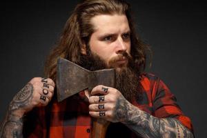 handsome man with long hair cuts his hair with an ax like a barbershop photo