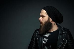 portrait of a handsome bearded man in a leather jacket and hat looking to the side photo