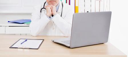 Portrait of senior doctor in medical office.Man in white uniform photo