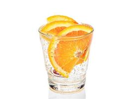 una rodaja de naranja con burbujas en un vaso de agua con gas. de cerca foto