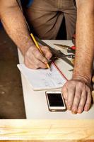The worker makes the necessary calculations and writes down the obtained digital result in a notebook with a pencil. photo