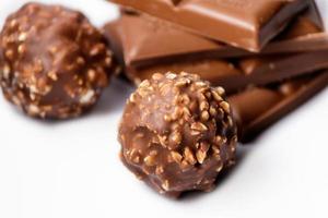 Vista superior de bolas de caramelo de chocolate con barras de chocolate sobre una superficie blanca foto