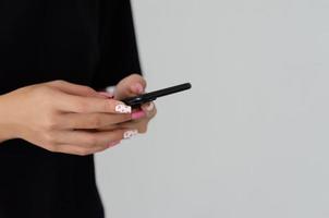 Mano femenina sosteniendo un teléfono con un hermoso esmalte de uñas rosa espacio de copia. foto