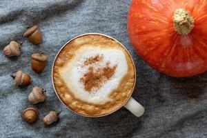 Closeup shot of cappuccino, red pumpkin, and acorns photo