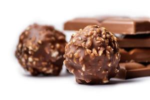 El enfoque selectivo de bombones de chocolate cubiertos con nueces con barras de chocolate en el fondo foto