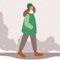Girl in a  green coat walking in a winter park. First snow. Christmas mood. Stylish hat with a pompom.