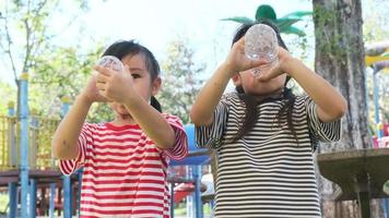 niñas bebiendo agua mineral de botellas en el patio de recreo al aire libre video