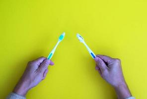 Hand holding a toothbrush with teeth isolated on a yellow backdrop with healthcare theme photo