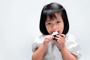 Happy girl biting chocolate cake tasty. Kid is yummy bakery. photo