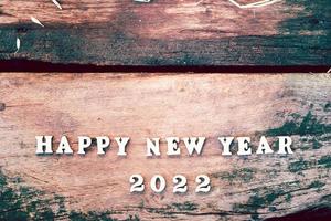 White wood text Happy New Year 2022 on brown wooden plank. Empty space for enter text. photo