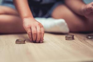 La mano de la niña pequeña contaba monedas de plata que yacían en el suelo. concepto de ahorro.