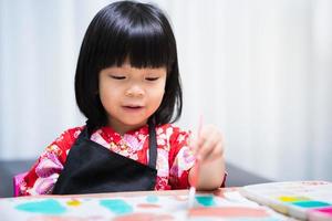 Cuadro de pintura de niña niño feliz con pincel en estudio de casa. dulce sonrisa. foto