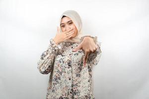 Hermosa joven musulmana con la mano cubriendo la boca, la mano apuntando hacia abajo, mostrando expresión de desaprobación, mostrando disgusto por algo, aislado sobre fondo blanco. foto