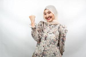 Beautiful young asian muslim woman smiling confident, enthusiastic and cheerful with hands clenched, sign of success, punching, fighting, not afraid, victory, isolated on white background photo