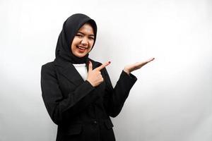 Beautiful young asian muslim business woman with hands showing and presenting something in the direction of empty space, smiling confidently, excitedly, facing the camera, isolated on white background photo