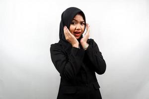 Hermosa joven mujer de negocios musulmana asiática conmocionada, sorprendida, expresión guau, con la mano que sostiene la mejilla frente a la cámara aislada sobre fondo blanco foto