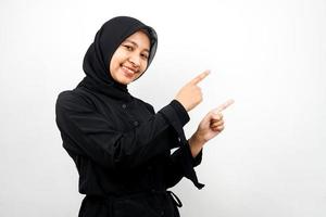 Beautiful young asian muslim woman smiling confident, enthusiastic and cheerful with hands pointing empty space presenting something facing camera isolated on white background, advertising concept photo