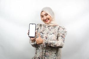 Hermosa joven musulmana asiática sonriendo con confianza y entusiasmo con las manos sosteniendo el teléfono inteligente, promoviendo la aplicación, mano de signo ok, buen trabajo, éxito, aislado sobre fondo blanco. foto