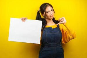 Pretty and cute young woman sad, dislike, hand holding blank empty banner, placard, white board, blank sign board, white advertisement board, presenting something in copy space, promotion photo