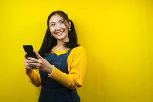 Pretty and cute young woman cheerful, confident, with hands holding smartphone, looking at empty space, promoting product, presenting something, advertisement, isolated photo